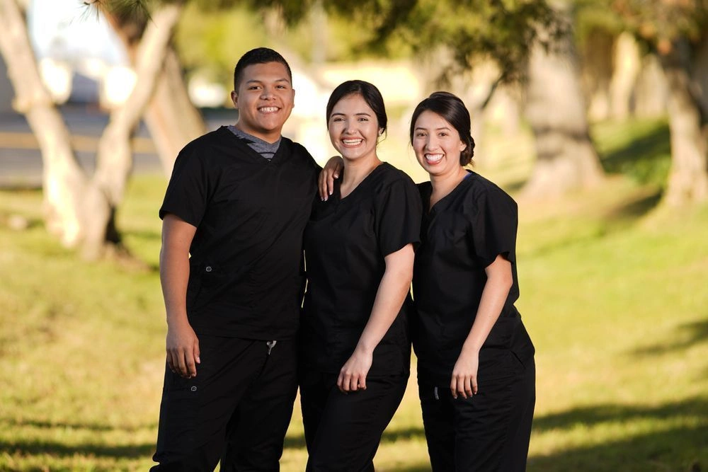 Group of {{ school.name }} students posing together in scrubs outside of school facility